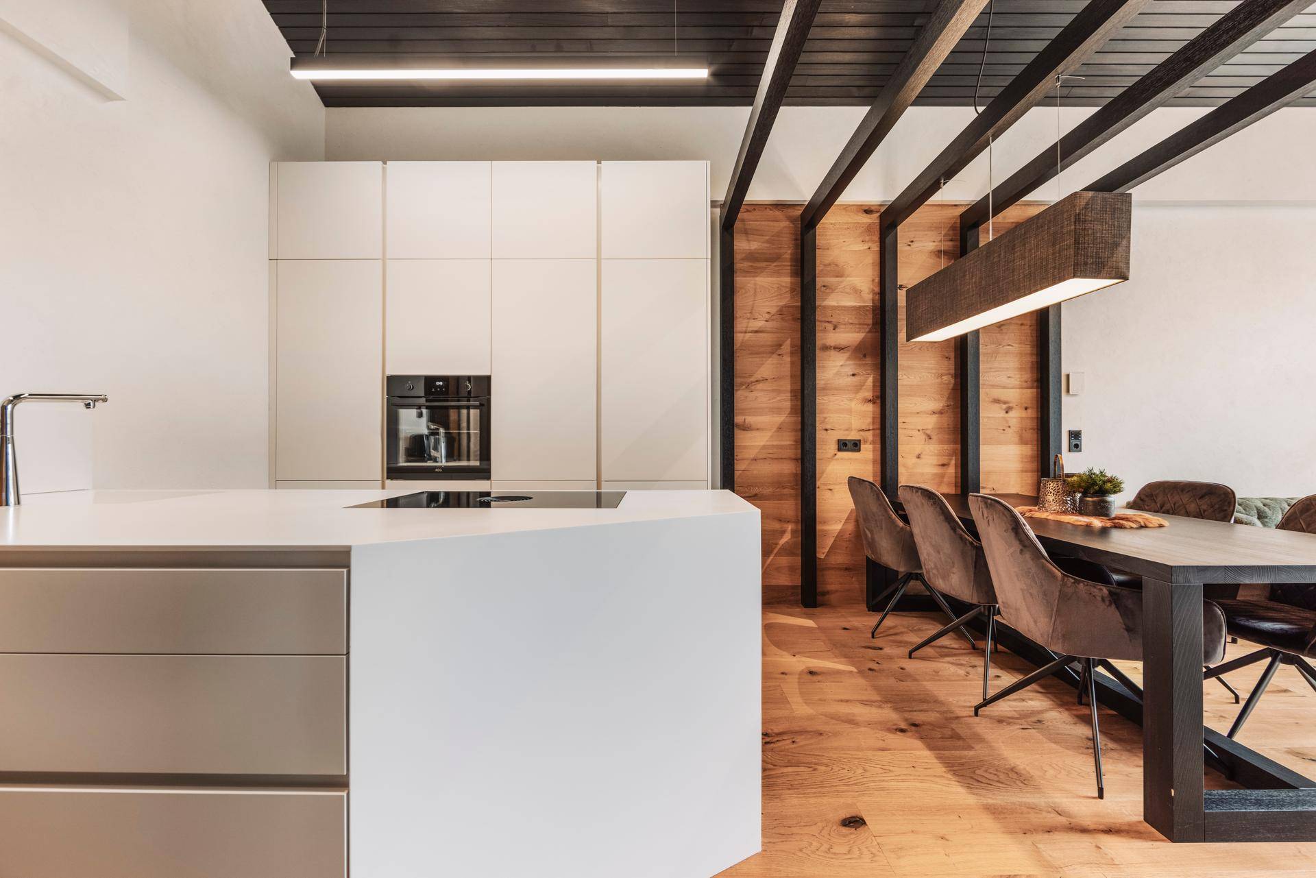 Helle, moderne Küche mit Kochinsel und integrierten Geräten, offen zum Essbereich.