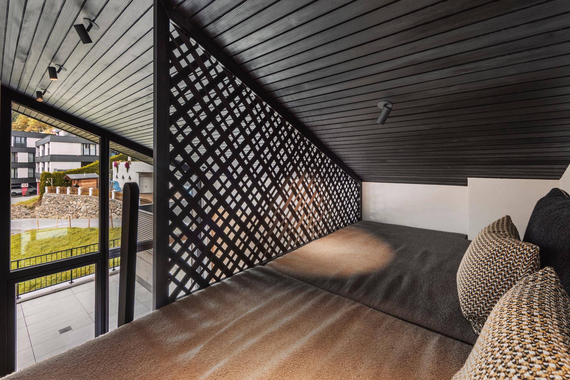 Gemütlicher Schlafbereich im Dachgeschoss mit Teppichboden und Blick nach draußen.