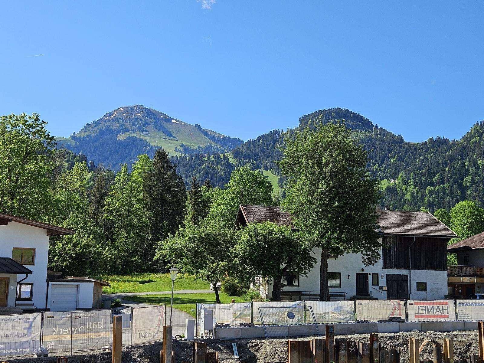 Blick auf bewaldete Berge und ländliche Umgebung mit einigen Häusern und einer Baustelle.