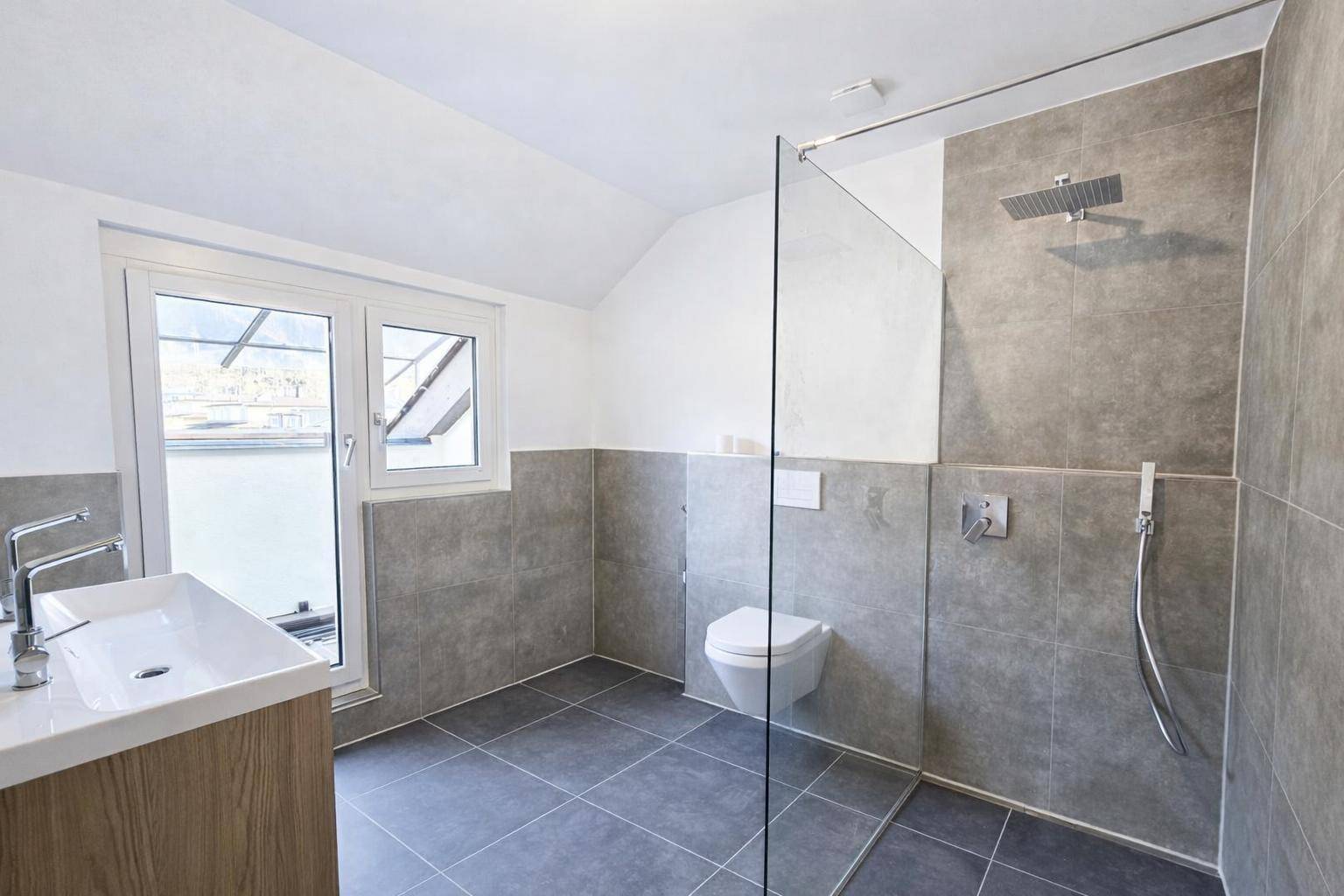 Modernes Badezimmer mit ebenerdiger Dusche, Wand-WC, Einzelwaschbecken und einem Fenster für Tageslicht.