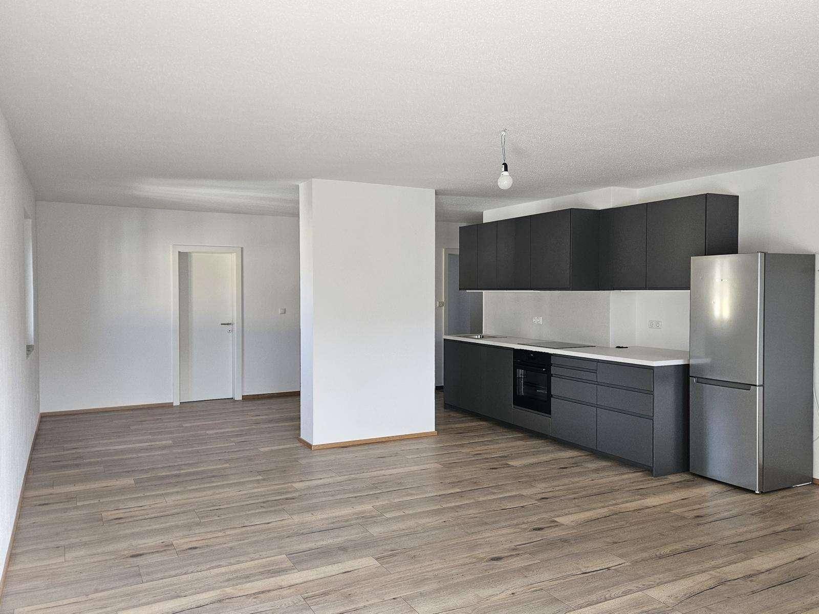 Heller offener Wohnbereich mit integrierter Küche und modernem Holzfußboden.