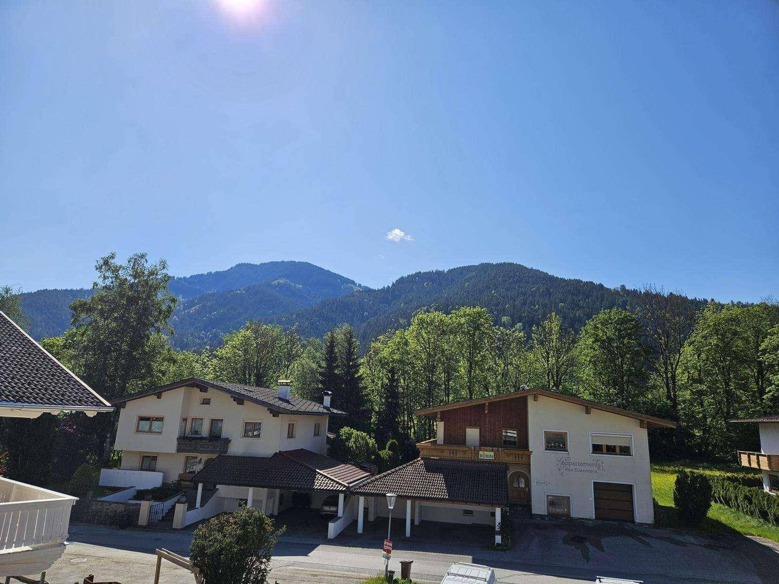 Wohngebiet mit traditionellen Häusern vor einer Kulisse aus bewaldeten Bergen.