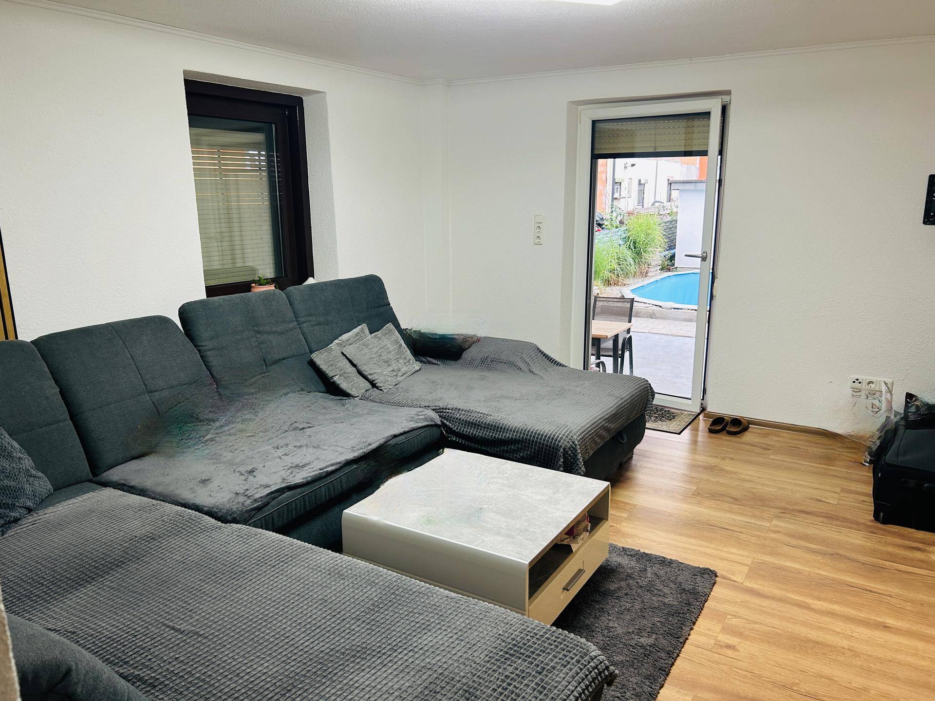 Gemütliches Wohnzimmer mit großem Ecksofa, Holzboden und direktem Zugang zum Außenbereich mit Pool.