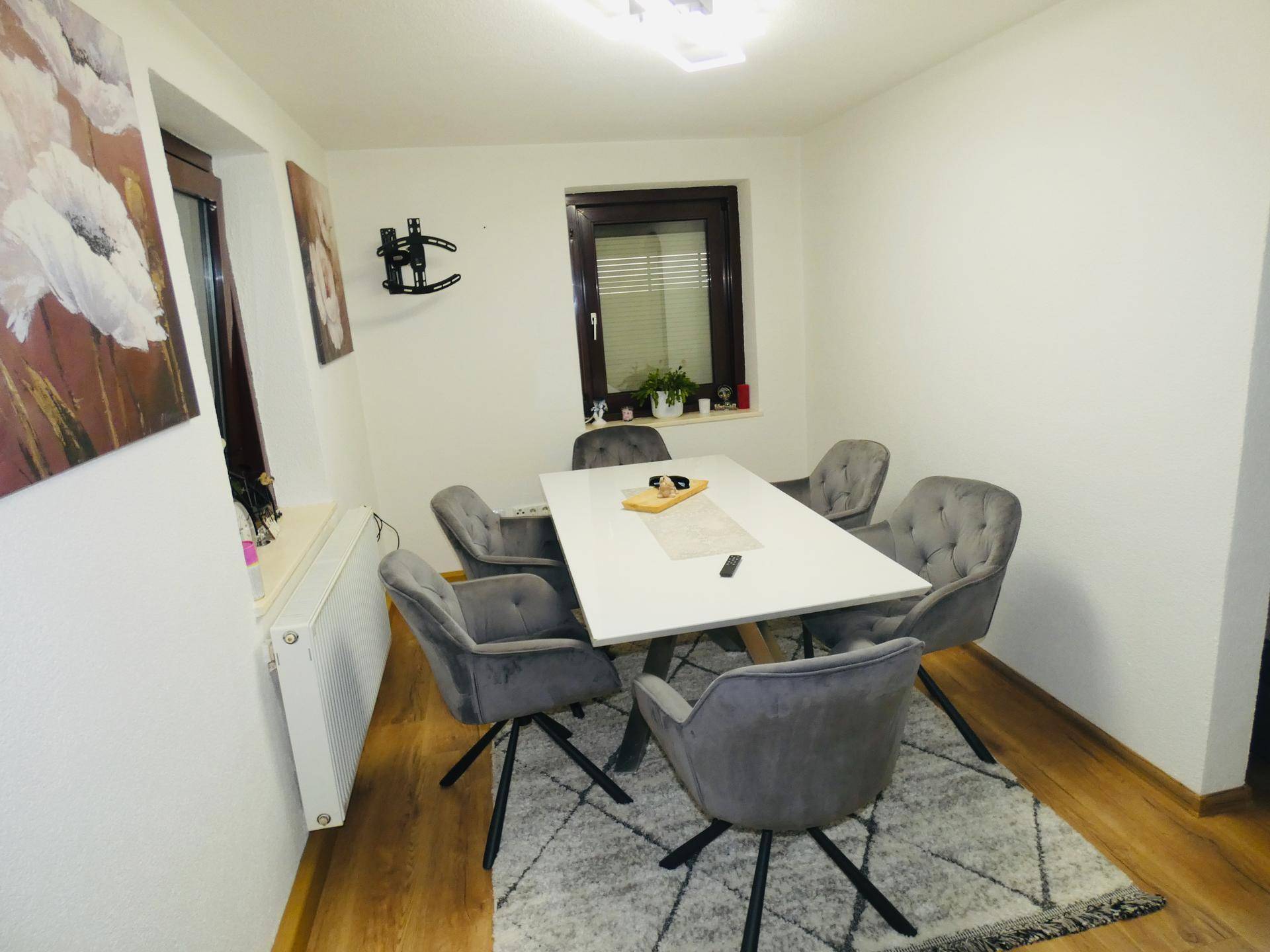 Heller Essbereich mit modernem Esstisch, grauen Stühlen und Holzboden, ideal für Familienmahlzeiten.