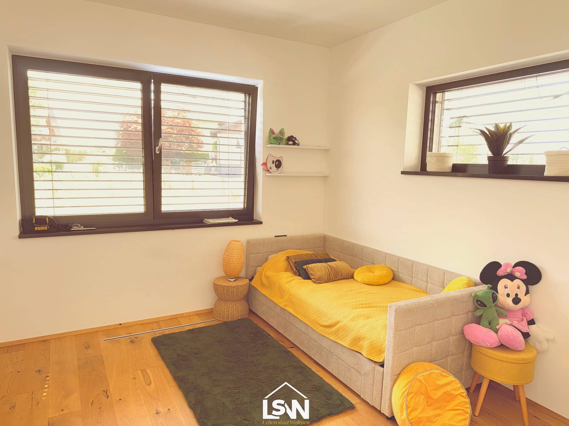 Gemütliches Kinderzimmer mit Einzelbett, Holzboden und großen Fenstern.