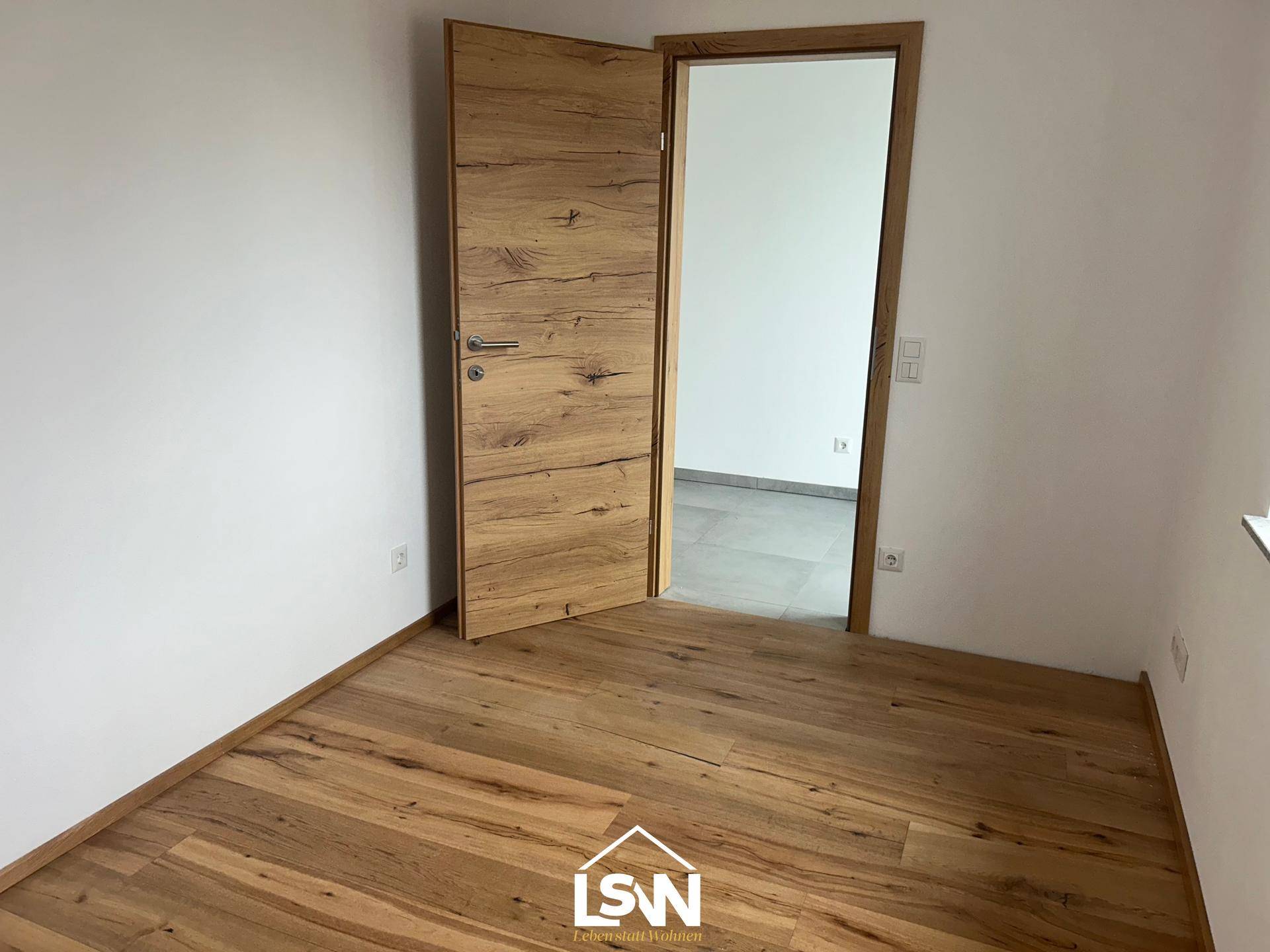 Heller Raum mit modernem Holzboden und weiß gestrichenen Wänden, bereit für die individuelle Gestaltung.