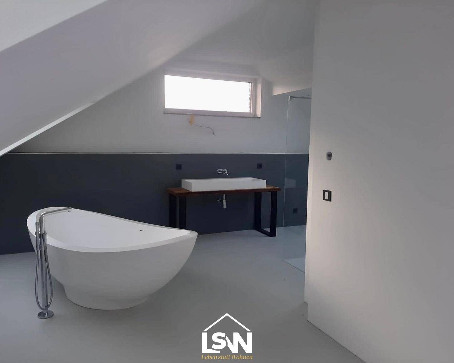 Modernes Badezimmer im Dachgeschoss mit freistehender Badewanne, Einzelwaschbecken und Dachfenster.