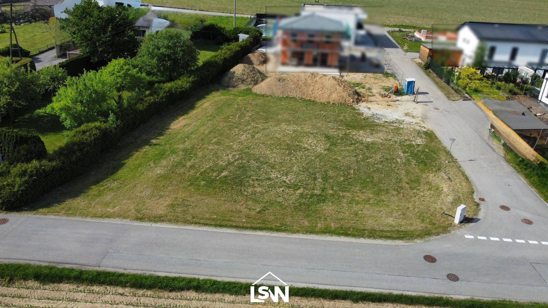 Übersicht des Baugrundstücks aus der Vogelperspektive mit angrenzender Baustelle und Hecke.