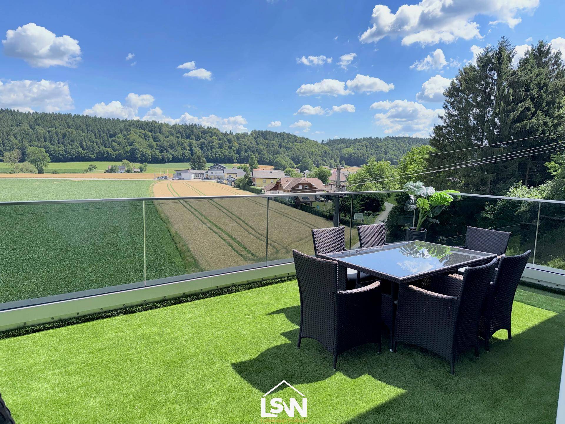 Geräumige Terrasse mit Esstisch und Stühlen, umgeben von einer malerischen Landschaft.