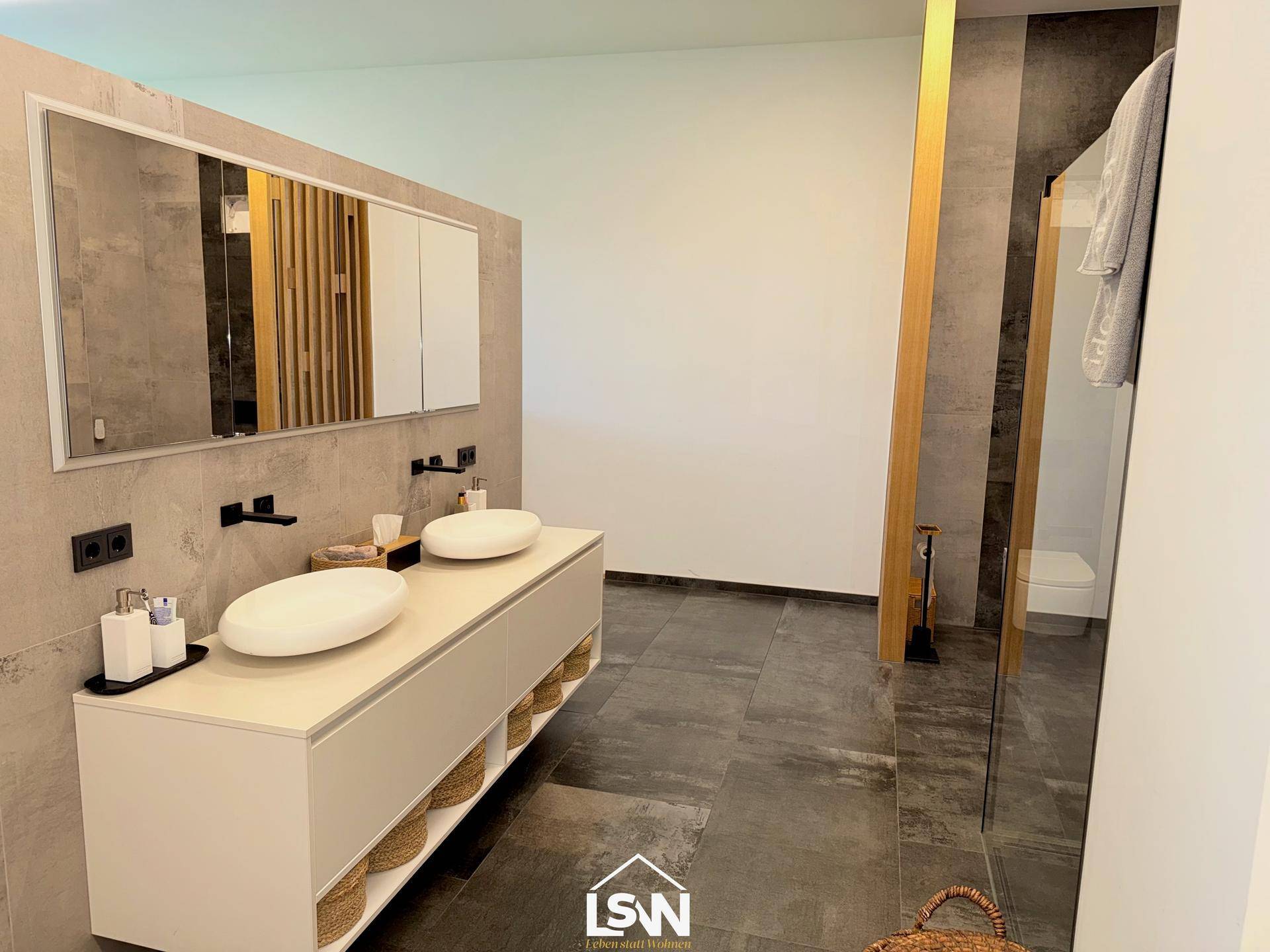 Elegantes Badezimmer mit Doppelwaschbecken, modernen Armaturen und begehbarer Dusche.