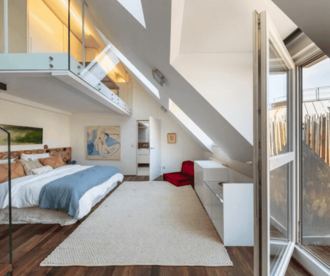 Geräumiges Schlafzimmer mit Holzboden, Dachschrägen und Zugang zur Terrasse.