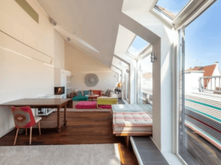 Helles Wohnzimmer mit Kamin, Holzboden und großen Fenstern zur Dachterrasse.