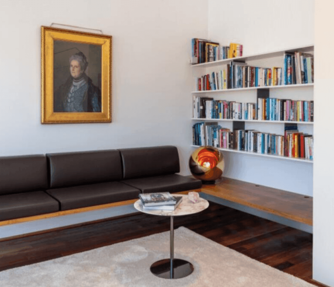 Gemütlicher Wohnbereich mit Bücherregal, Ledersofa und Kunst an der Wand.