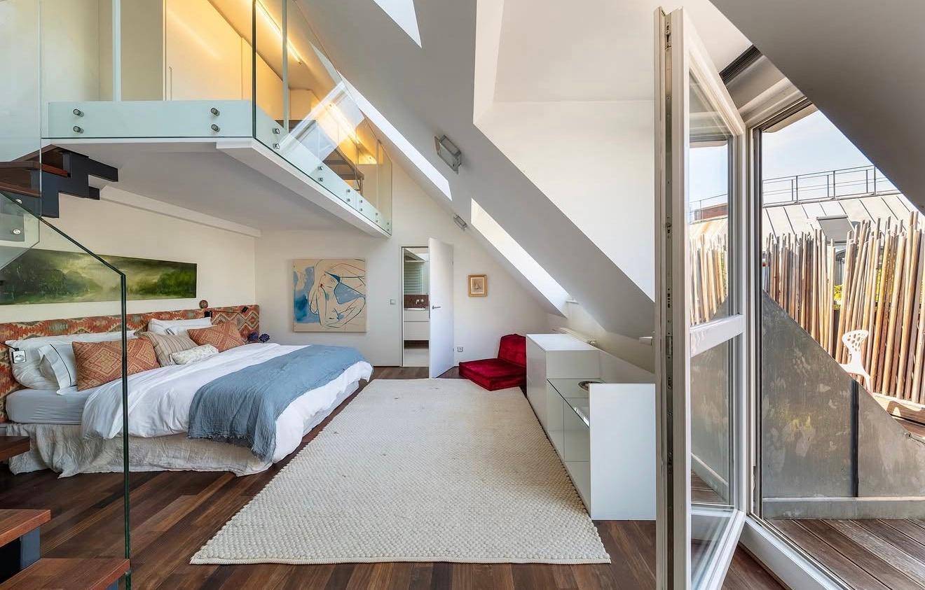 Helles Schlafzimmer mit Holzboden, Zugang zur Terrasse und offener Galerie.