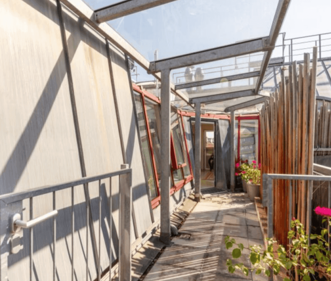 Dachterrasse mit Metallgeländer, Glasdach und Blick auf die Umgebung.