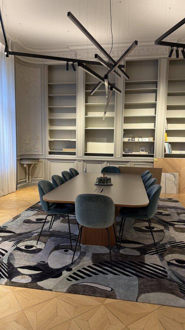 Geräumiger Konferenzraum mit langem Tisch, bequemen Stühlen und integrierten Bücherregalen an der Wand.
