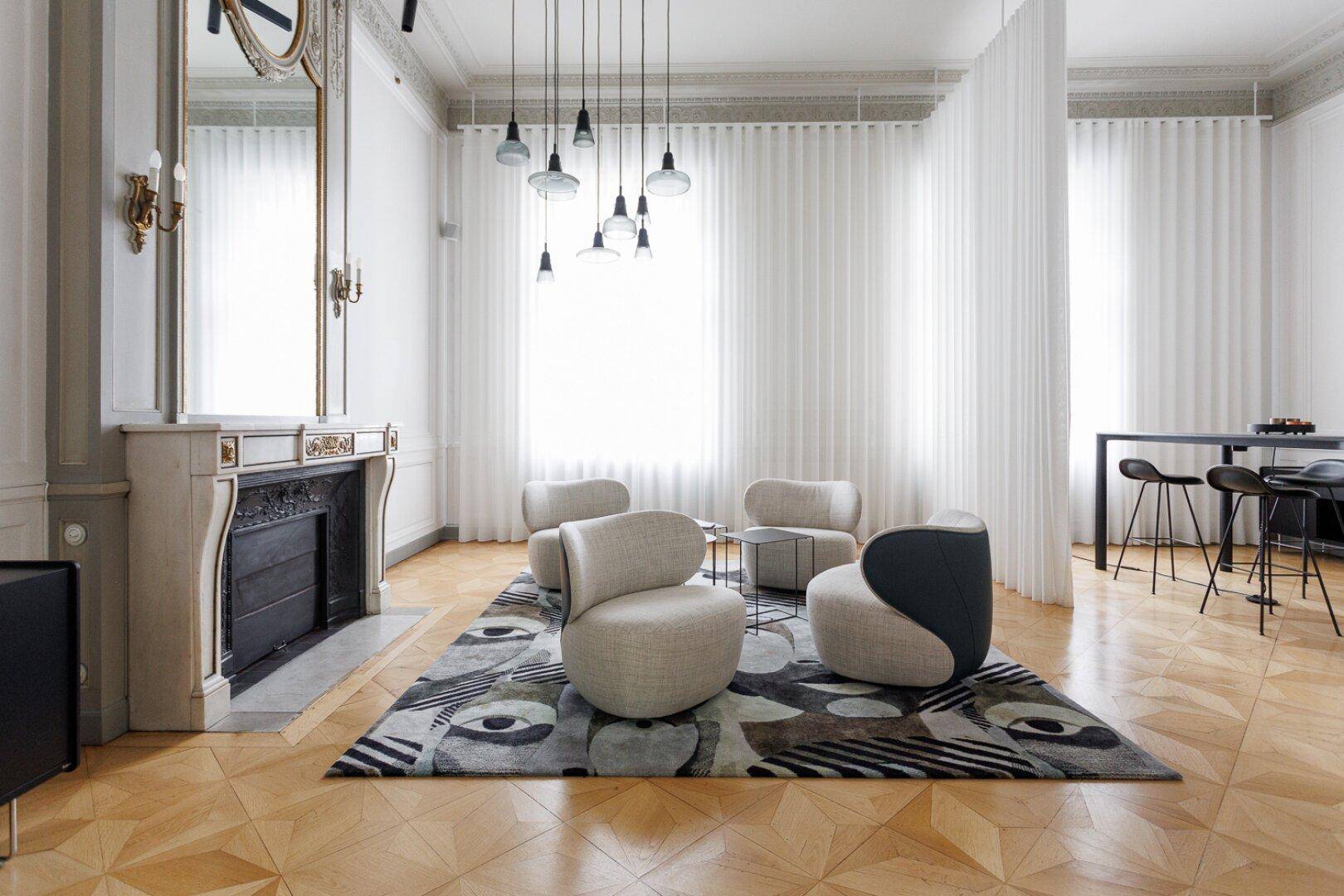 Helles Wohnzimmer mit hohen Fenstern, modernen Sitzgelegenheiten und einem stilvollen Kamin.