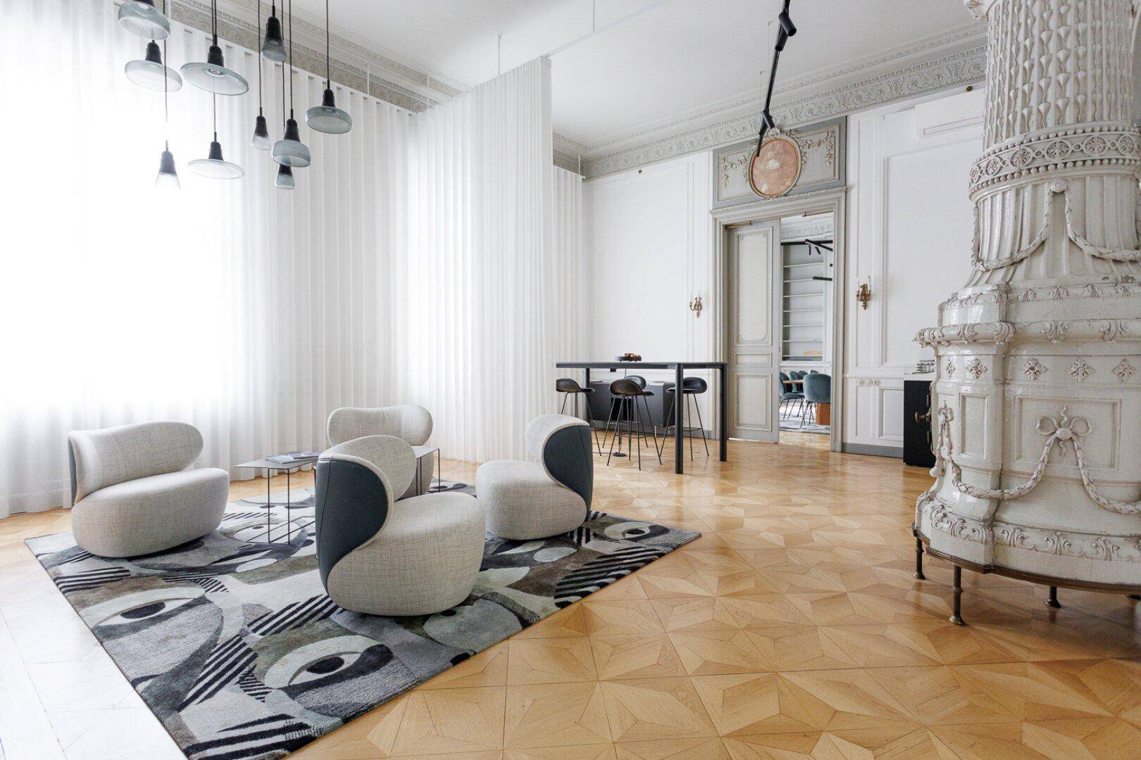 Elegantes Zimmer mit traditionellem Kachelofen, Fischgrätparkett und modernen Designermöbeln.