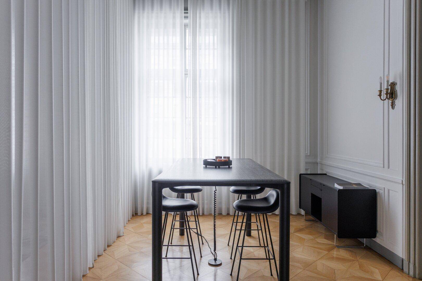 Moderner Essbereich mit hohem Tisch, Barhockern und hellen Vorhängen am Fenster.