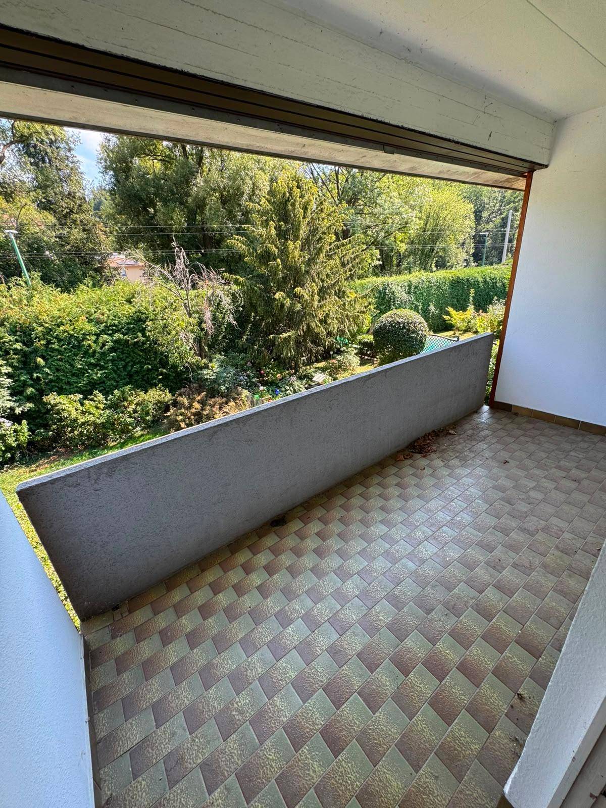 Überdachter Balkon mit Fliesenboden und Blick ins Grüne, ideal zum Entspannen.