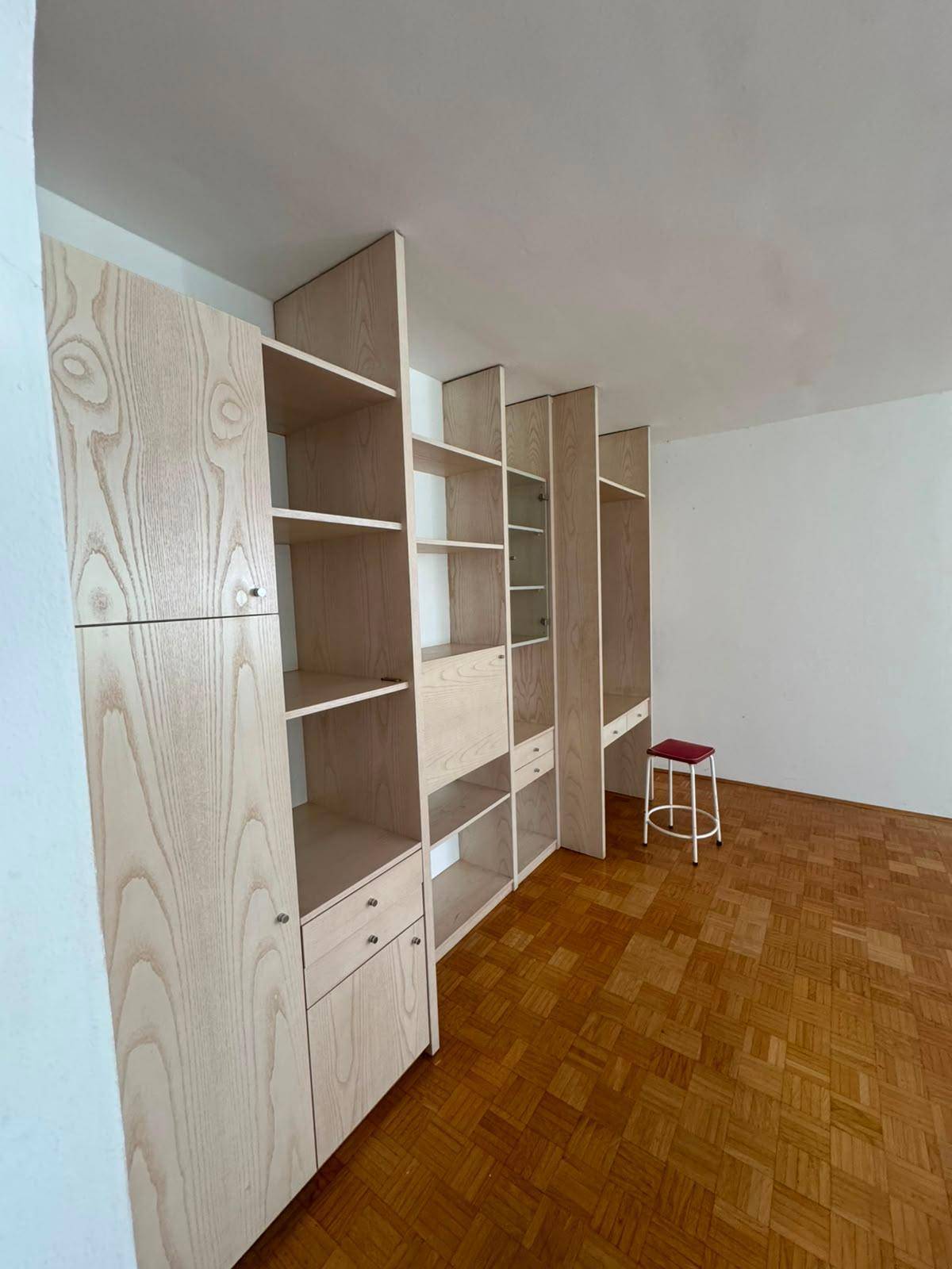 Heller Raum mit Parkettboden und eingebauten Holzregalen, bietet viel Stauraum.