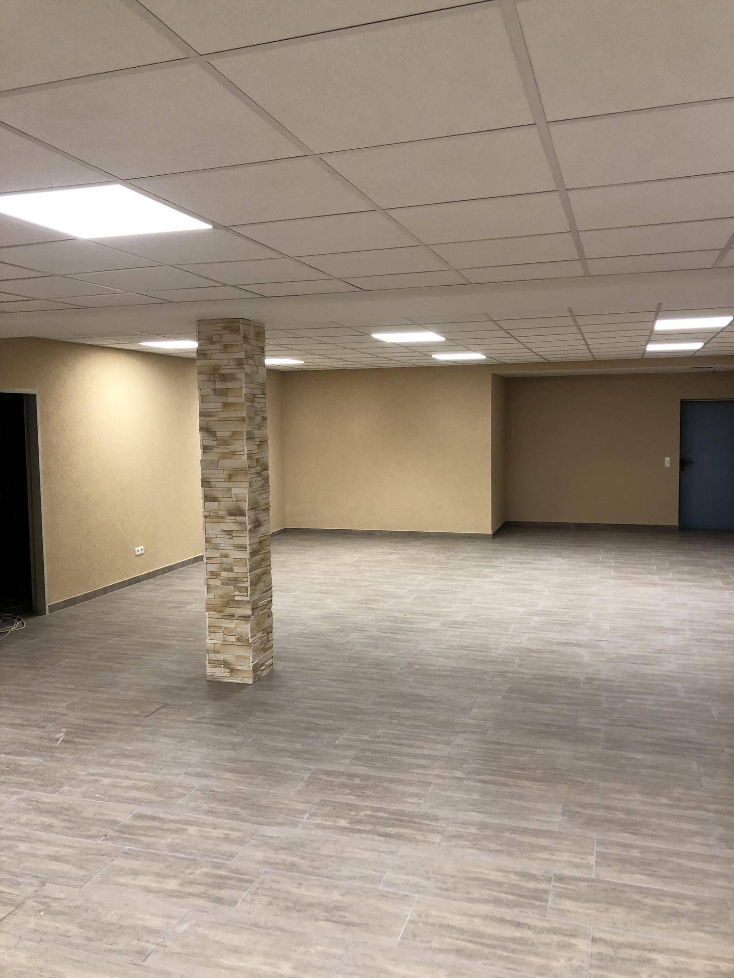 Geräumiger Innenraum mit hellen Fliesen, abgehängter Decke und einem zentralen, steinverkleideten Pfeiler.