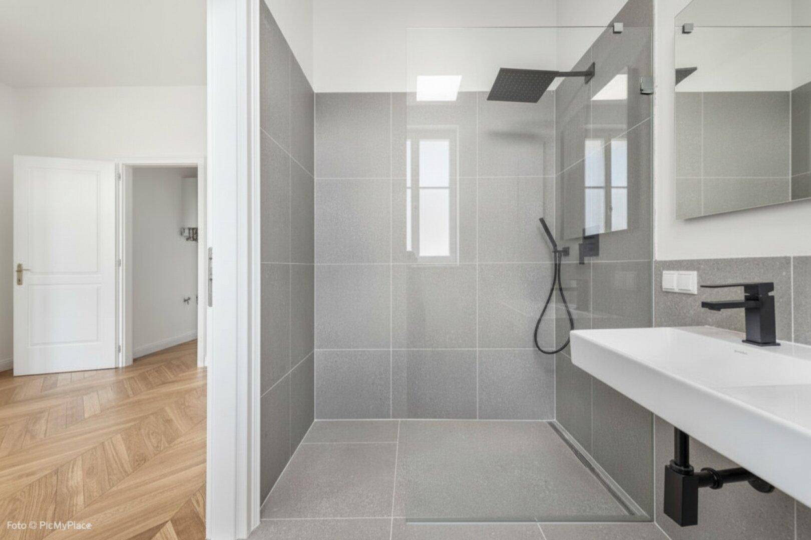 Modernes Badezimmer mit großer ebenerdiger Dusche und minimalistischem Design.