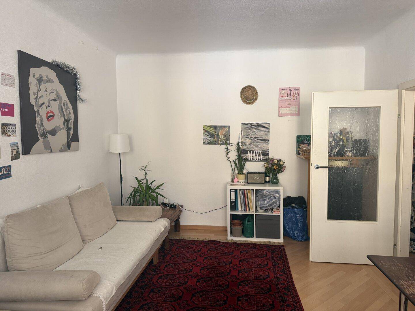 Gemütliches Wohnzimmer mit hellem Sofa, Holzboden und dekorativem Teppich.