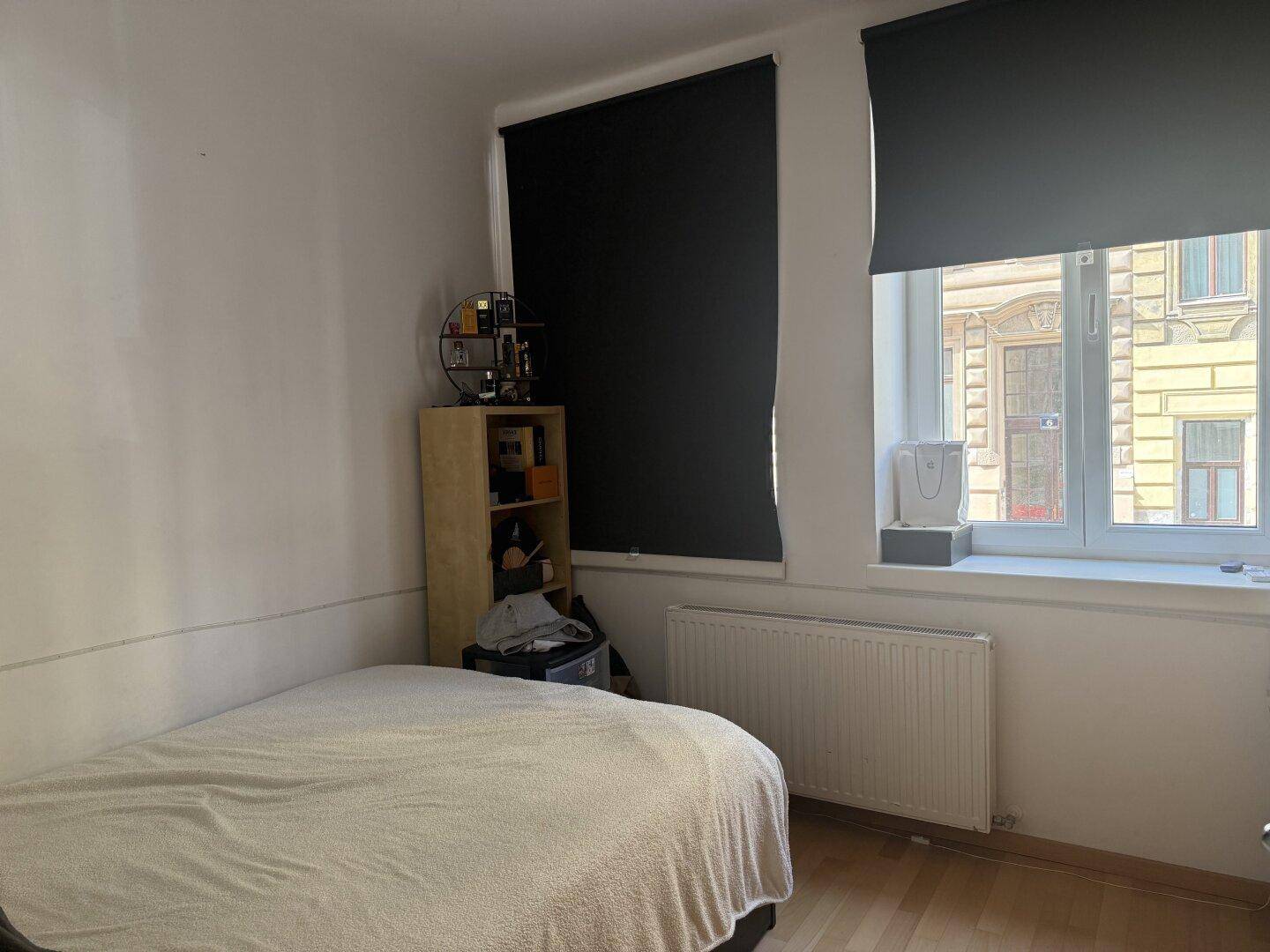 Schlafzimmer mit Einzelbett, Holzfußboden und Fenster mit Blick auf die Straße.