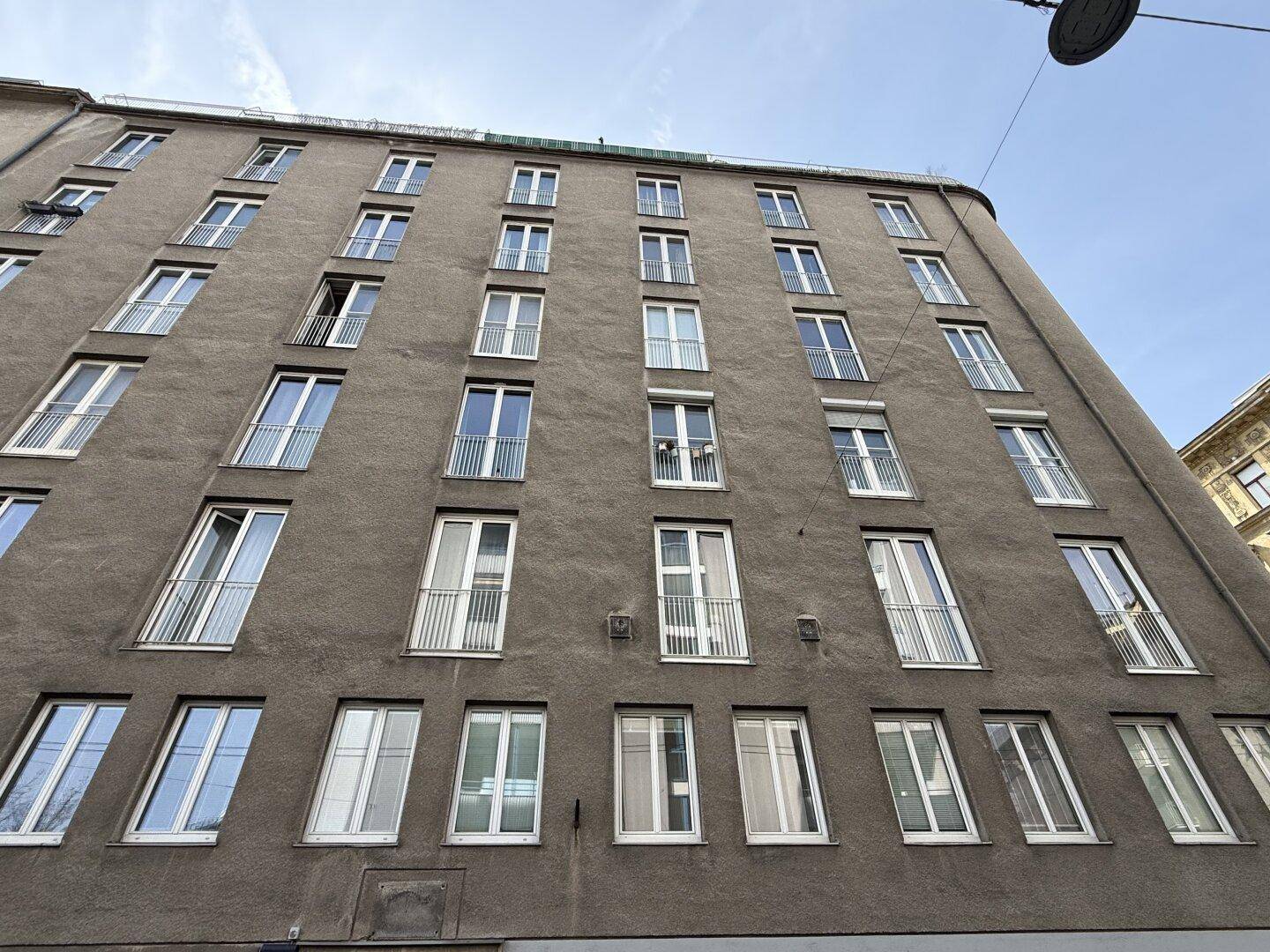 Fassade eines Mehrfamilienhauses mit vielen Fenstern und französischen Balkonen.