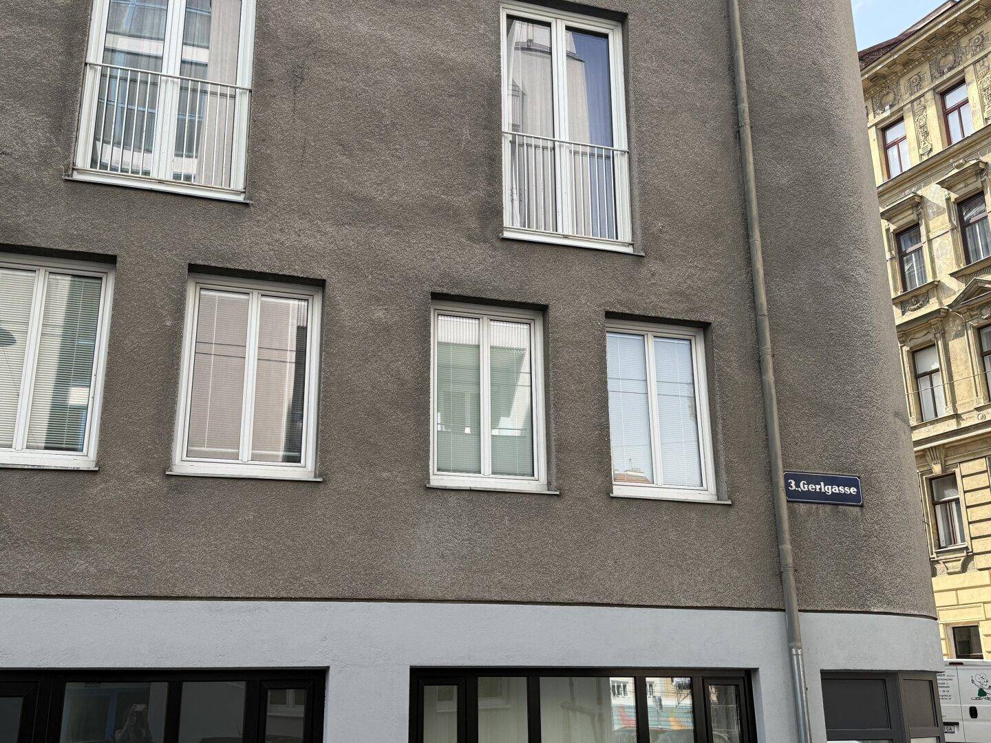 Eckansicht des Gebäudes mit Straßenschild und Fenstern.