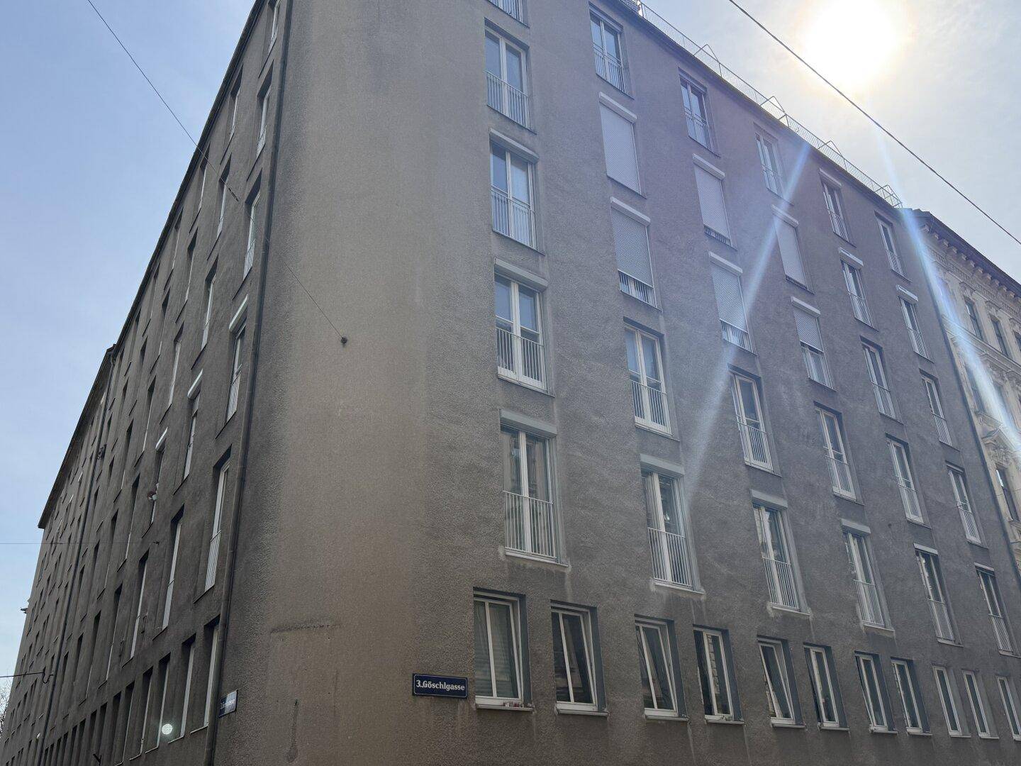 Gebäudefassade von der Straße aus gesehen mit vielen Fenstern und Balkonen.