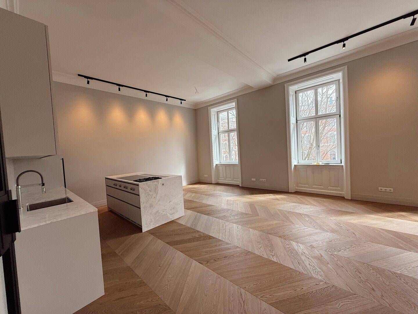 Helle, moderne Küche mit Kochinsel und Fischgrätparkett in einem großzügigen Raum.