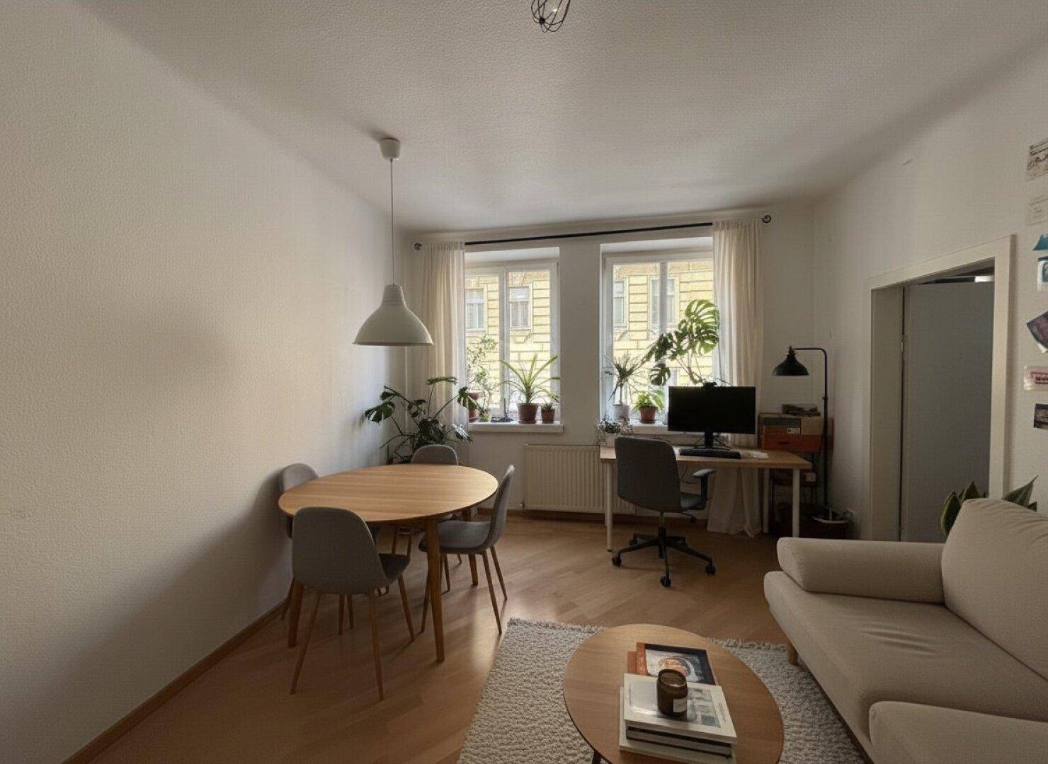Heller Wohn- und Essbereich mit Home-Office-Ecke am Fenster und modernem Mobiliar.