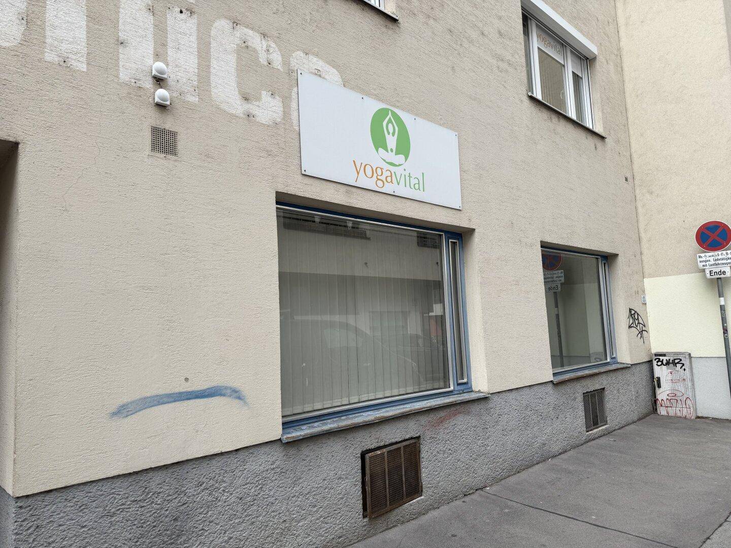Fassade eines Gebäudes auf Straßenniveau mit einem Geschäftsschild "yogavital" und großen Schaufenstern.