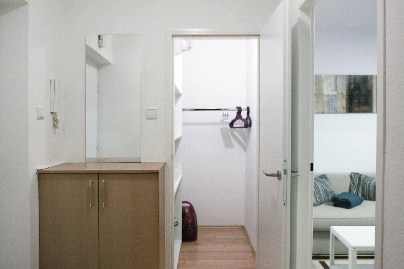 Heller Flur mit Garderobenschrank, Spiegel und Zugang zu weiteren Räumen.