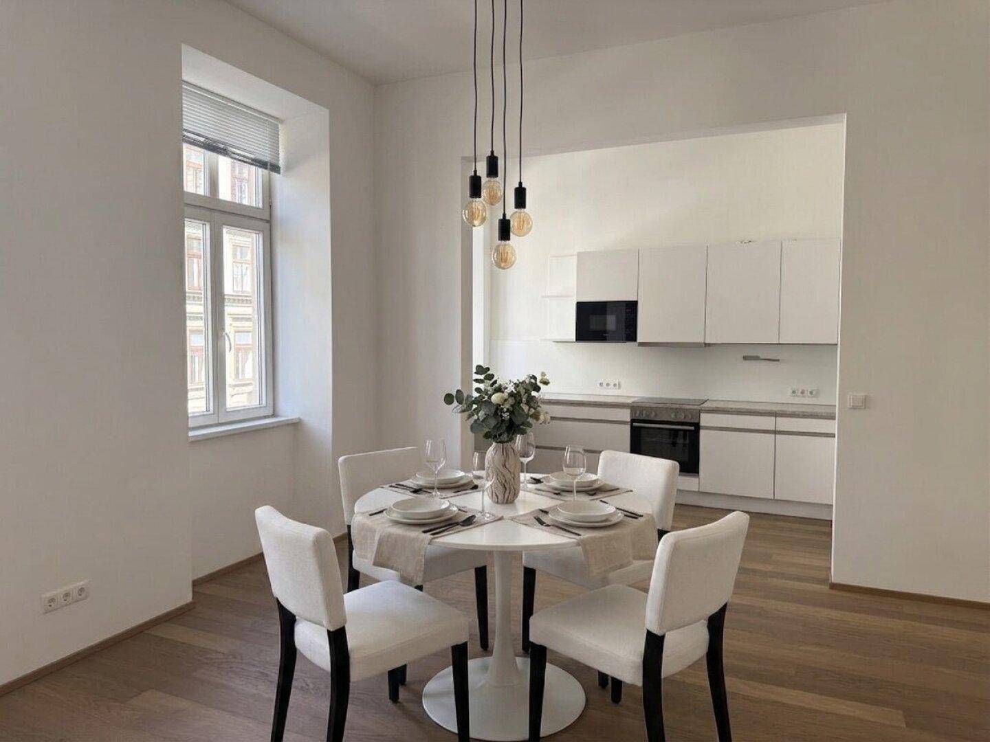 Helle, offene Küche mit modernen weißen Schränken, integriertem Essbereich und Holzboden.