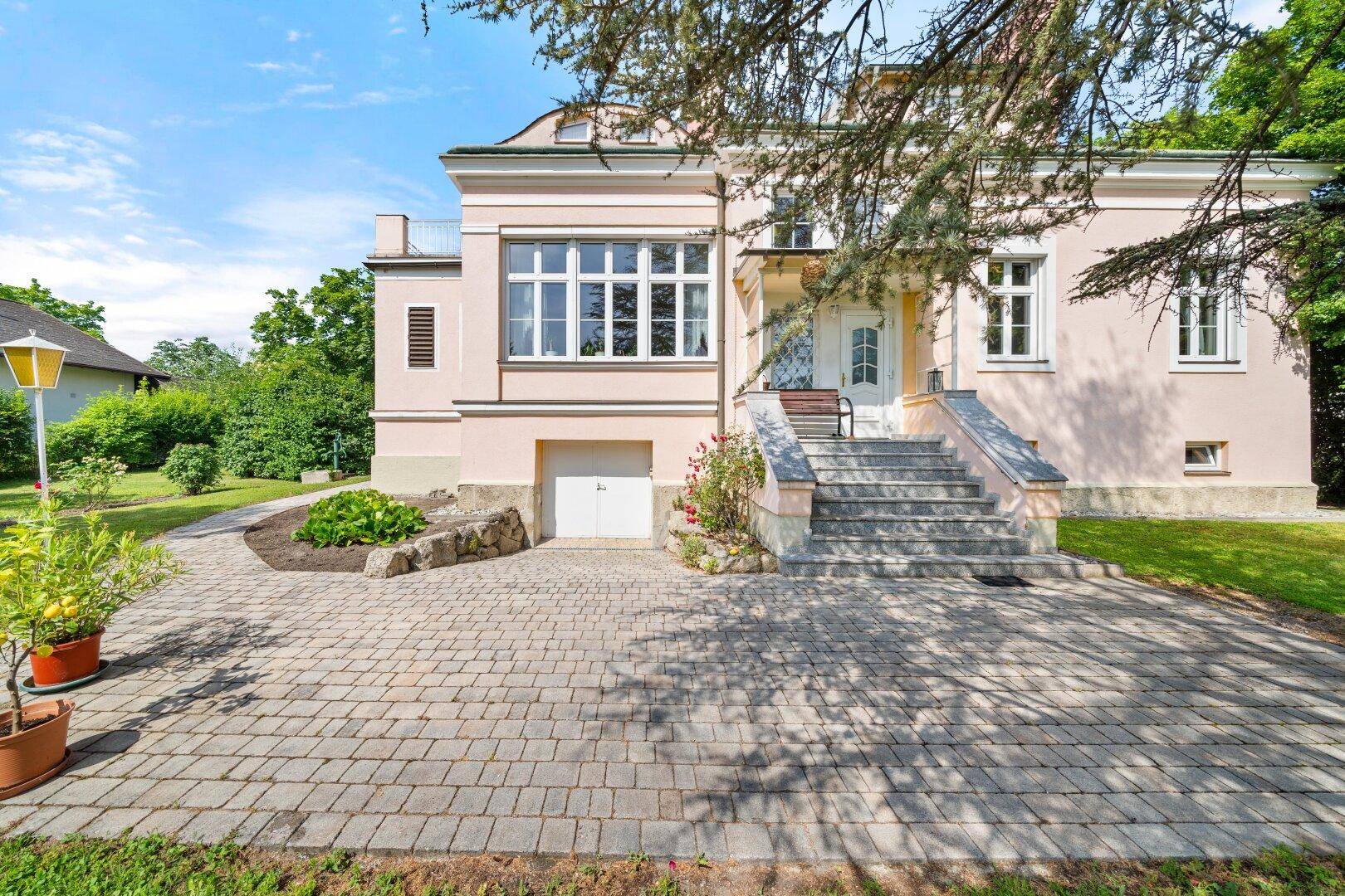 Vorderansicht des Hauses mit Eingang, gepflasterter Auffahrt und integrierter Garage.