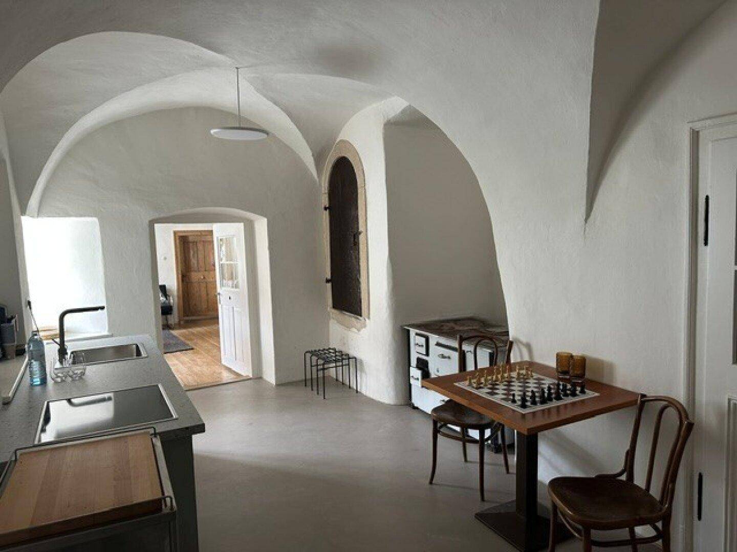 Moderne Küche mit gewölbter Decke, integrierter Spüle und einem charmanten Schachbrett-Esstisch.