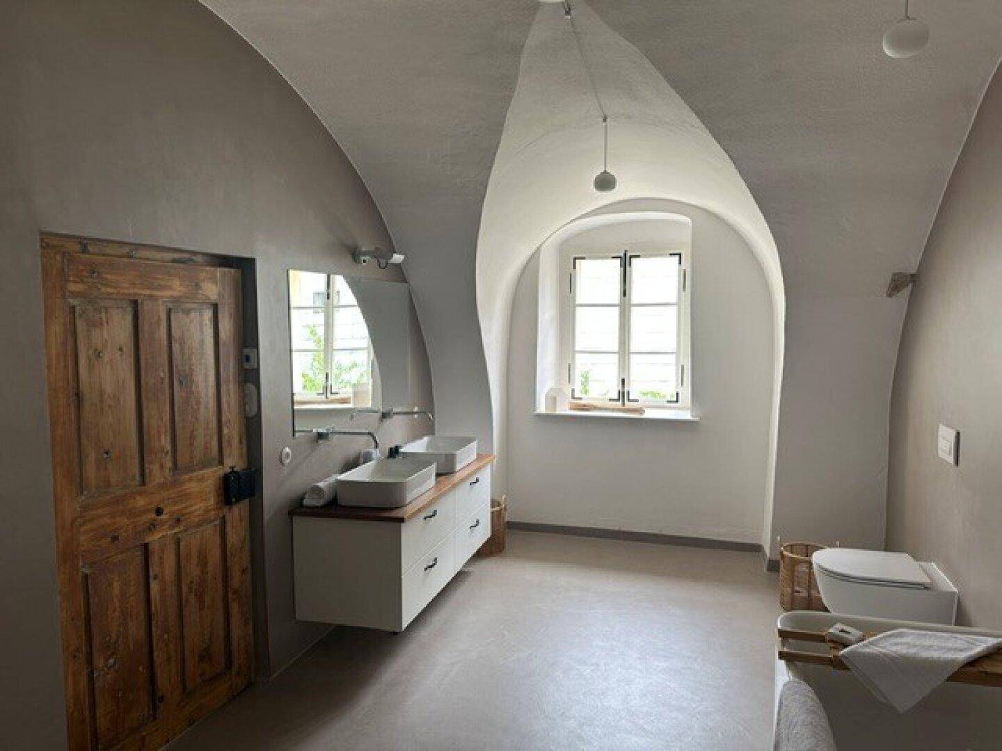 Modernes Badezimmer mit gewölbter Decke, Doppelwaschbecken und einem Fenster für natürliches Licht.