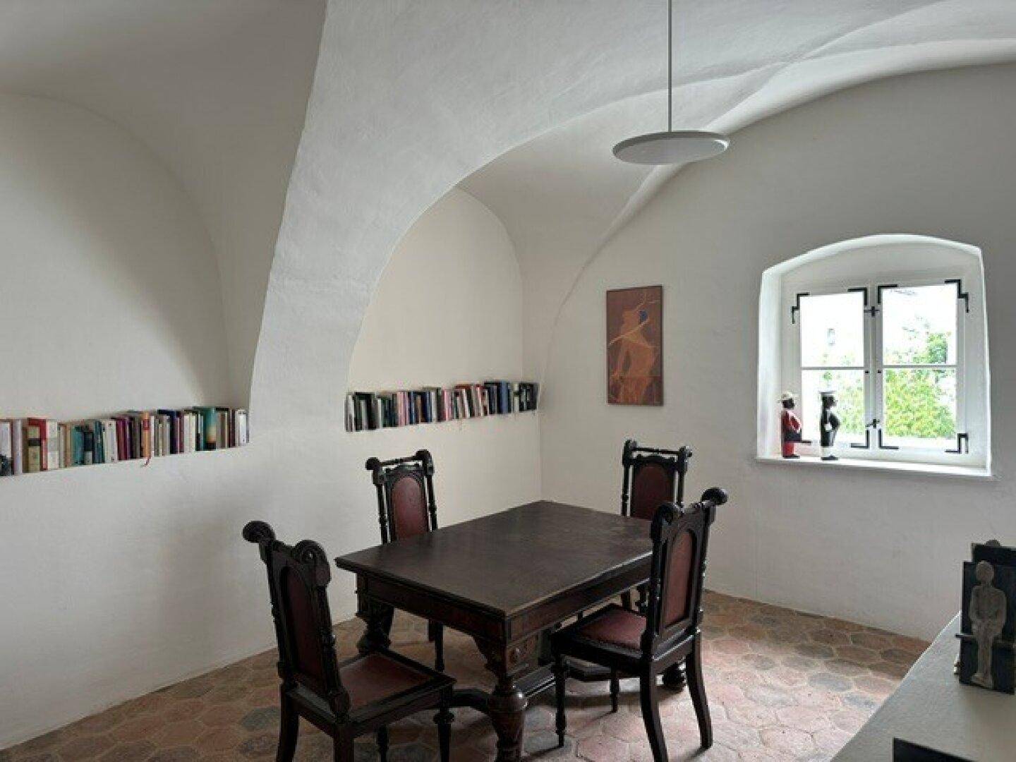 Traditioneller Essbereich mit gewölbter Decke, rustikalem Holztisch und Stühlen sowie einem Fenster.