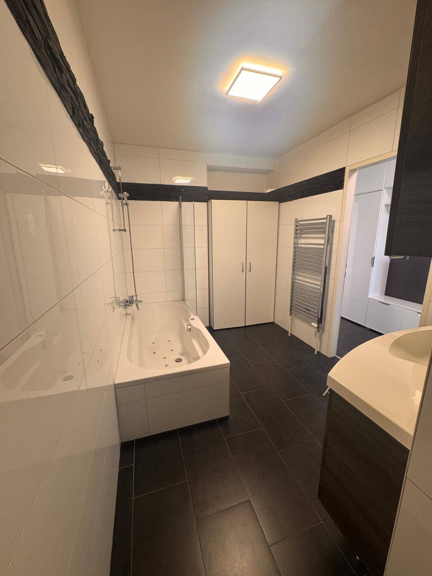 Modernes Badezimmer mit Badewanne, Dusche, Doppelwaschbecken und beheiztem Handtuchhalter.