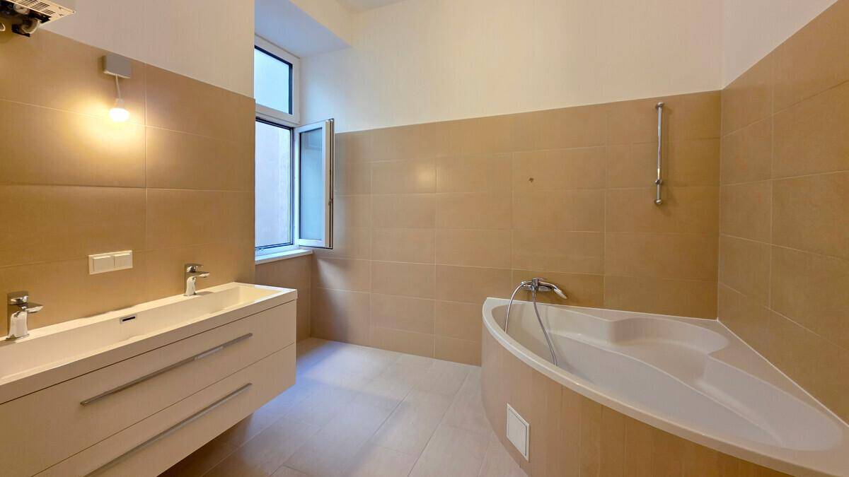 Modernes Badezimmer mit beigefarbenen Fliesen, Doppelwaschbecken und Eckbadewanne.