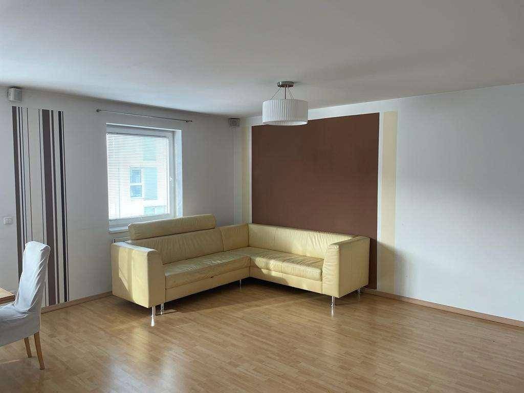 Wohnzimmer mit bequemem Ecksofa, Fenster und einer Akzentwand in Brauntönen.