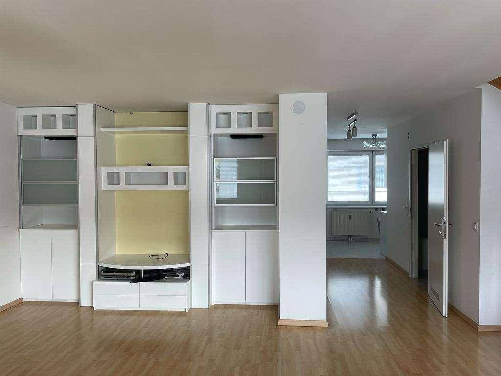 Geräumiges Wohnzimmer mit Einbauschränken und hellem Parkettboden.