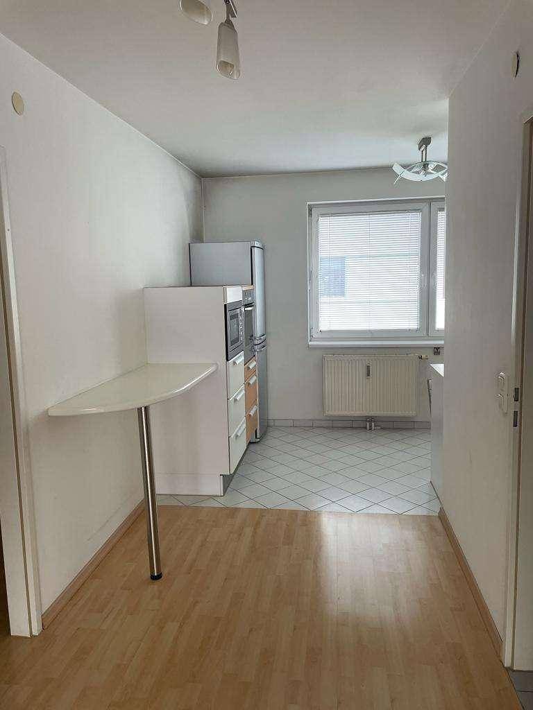 Übergang vom Wohnbereich zur Küche mit unterschiedlichen Bodenbelägen und Fenster.