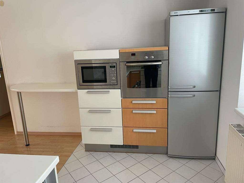 Küchenzeile mit Mikrowelle, Backofen und Kühlschrank, ergänzt durch praktische Schubladen.