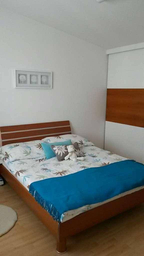 Gemütliches Schlafzimmer mit Holzbett, blauer Decke und integriertem Kleiderschrank.