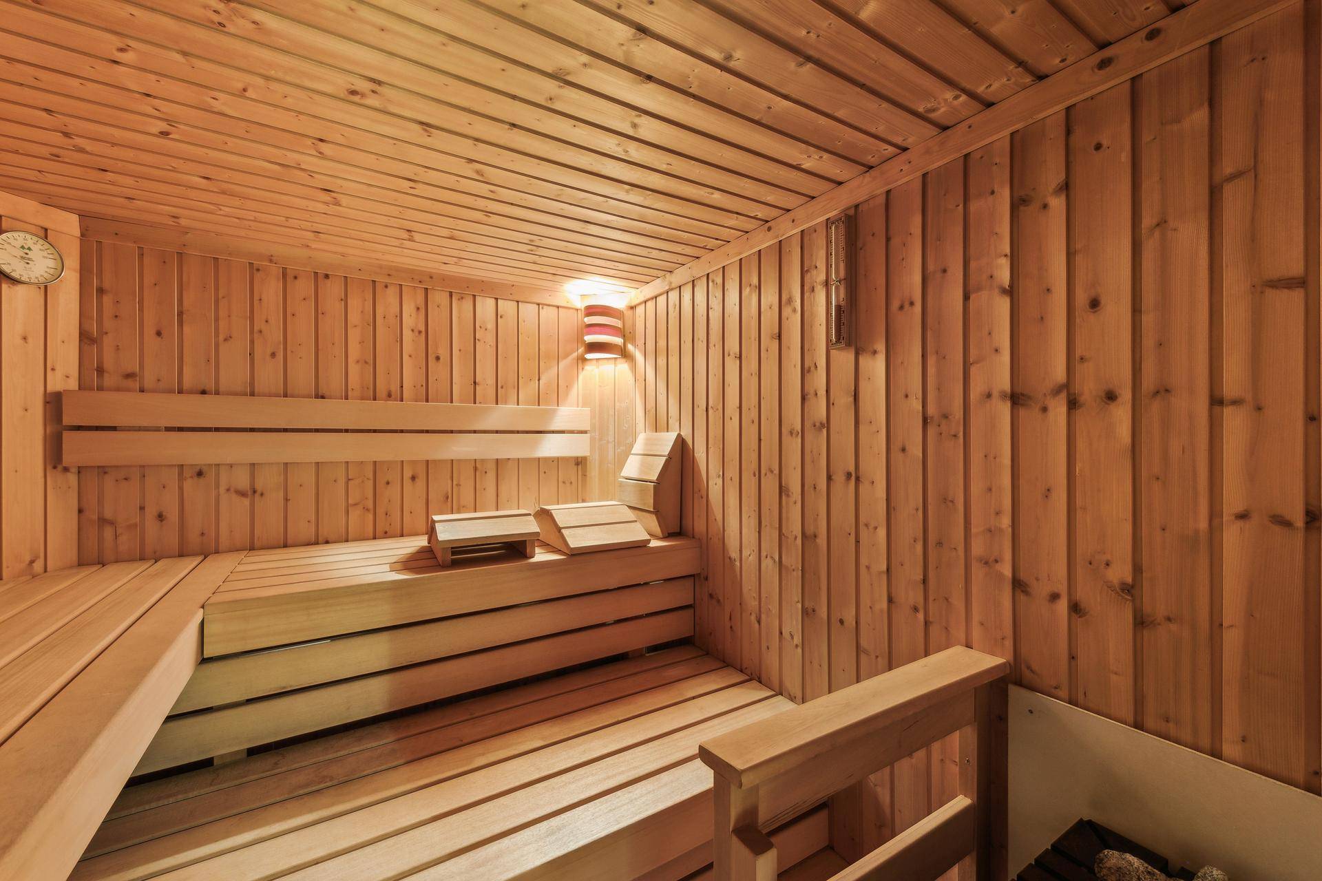 Traditionelle Holzsauna mit bequemen Bänken und angenehmer Beleuchtung für entspannende Momente.