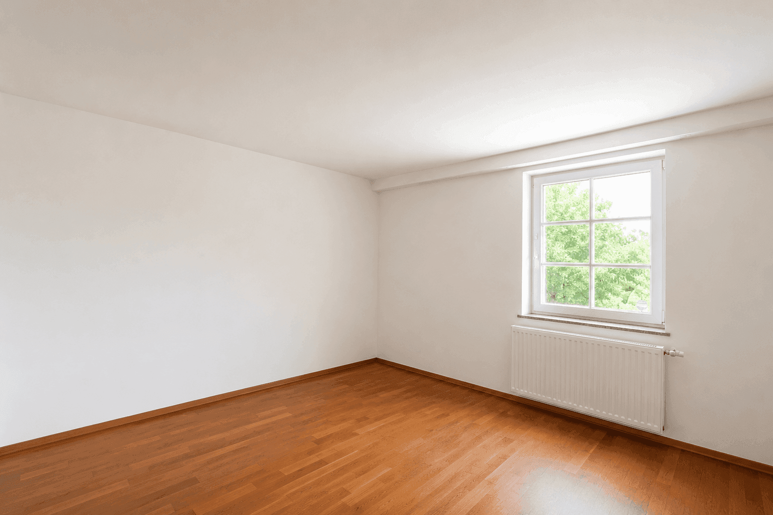 Leeres Schlafzimmer mit Holzboden, weiß gestrichenen Wänden und einem Fenster.
